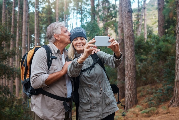 Pareja de ancianos toman selfie y caminan en el bosque gente feliz en la naturaleza y la memoria para la publicación en las redes sociales Sonríe en la foto aventura y fitness el anciano y la mujer están al aire libre con un estilo de vida activo