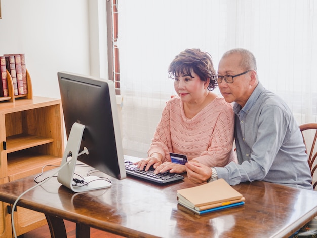 Foto pareja de ancianos usando la computadora junto con tarjeta de crédito en casa