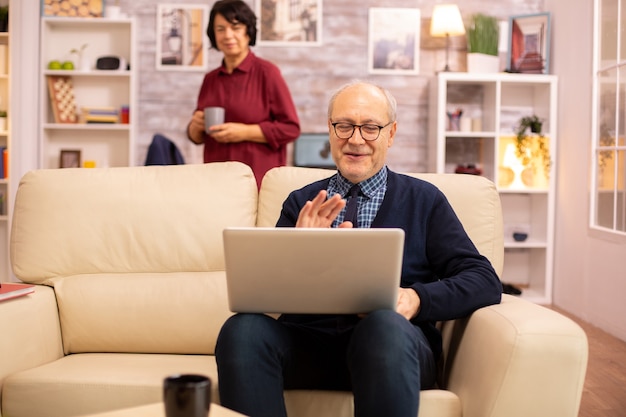 Pareja de ancianos usando una computadora portátil moderna para charlar con su nieto. Abuela y abuelo con tecnología moderna.