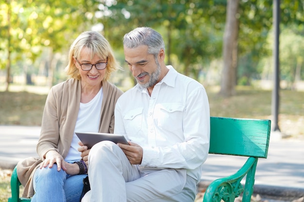 Pareja de ancianos usando una tableta en el parque