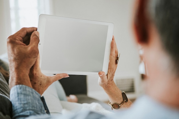 Pareja de ancianos usando una tableta en un sofá