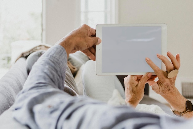 Pareja de ancianos usando una tableta en un sofá