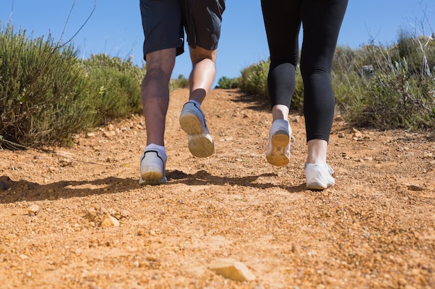 Pareja apta corriendo por el sendero de montaña