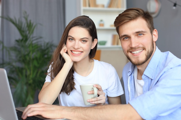 Pareja apuntando mientras trabajan juntos en la computadora portátil.