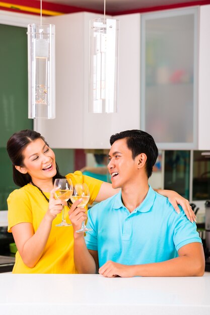 Pareja asiática bebiendo vino blanco en casa