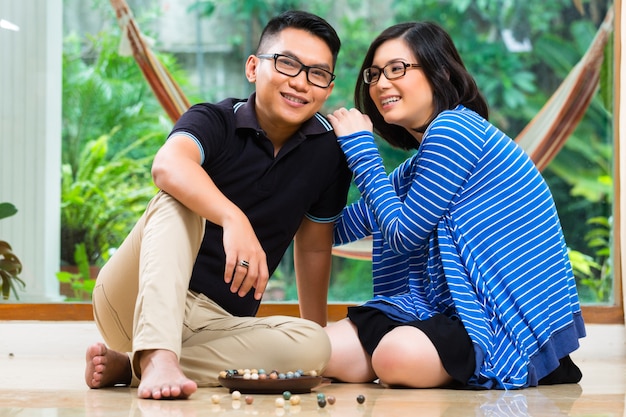 Pareja asiática en casa jugando con canicas