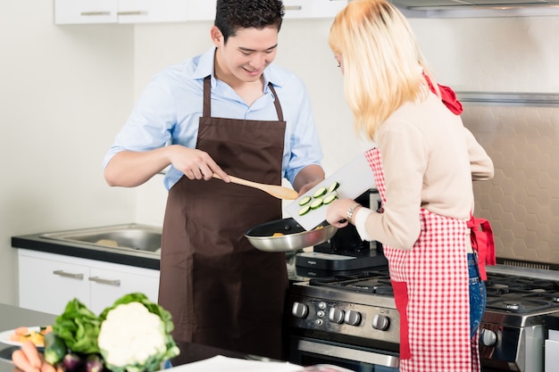 Pareja asiática cocinar verduras en una sartén