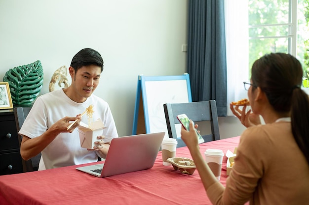 Pareja asiática comiendo fideos instantáneos y pizza juntos