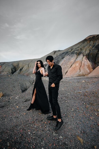 Una pareja asiática enamorada en ropa de cuero negro camina en la naturaleza entre los árboles. Estilo, moda, amor