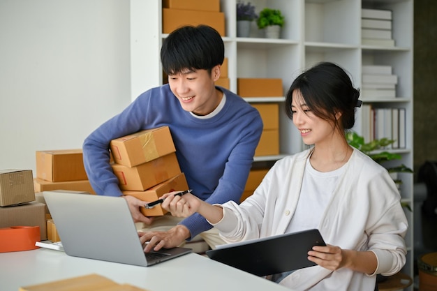 Una pareja asiática está hablando y revisando pedidos en el sitio web en la oficina juntos