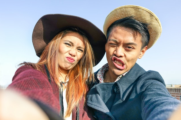 Pareja asiática hipster haciendo selfie con caras divertidas