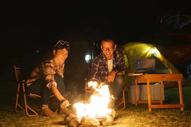 Una pareja asiática hornea maíz en un fuego que han puesto para iluminar la noche.