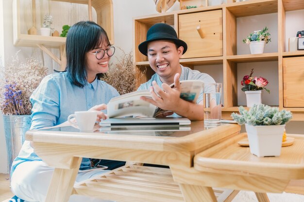 Pareja asiática leyendo la revista sobre el escritorio que tienen tecnología laptopn en wo moderno