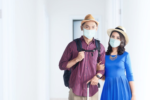 Pareja asiática en la mascarilla con bolsa de maleta y mochila en el hospital. Chequeo médico antes de viajar