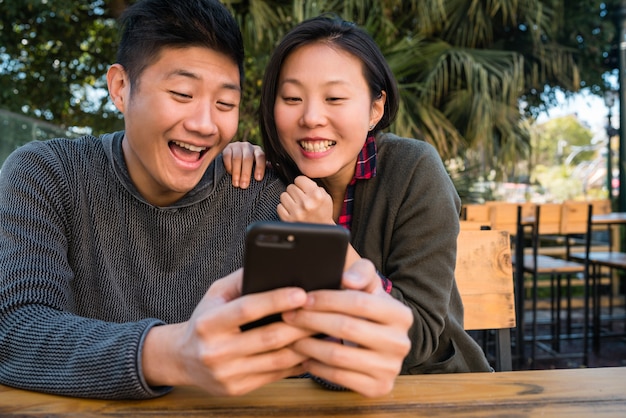 Pareja asiática mirando el teléfono móvil.