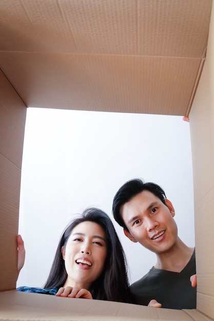 Pareja asiática mudarse a una nueva casa Abra una caja de cartón marrón grande. Sonrisa feliz. concepto de familia La pareja se mudó a una nueva casa para formar una familia.