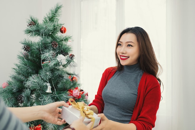 Pareja asiática de Navidad. Un hombre guapo dando a su novia / esposa un regalo en casa celebrando el Año Nuevo.