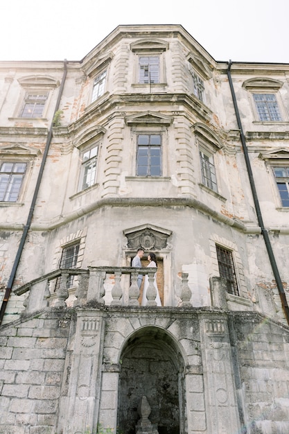 Foto pareja asiática de pie cara a cara en el balcón del antiguo castillo