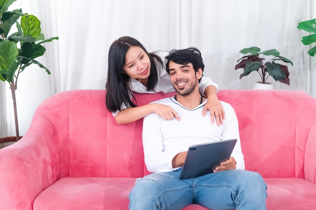 Pareja asiática sentada en el sofá con tablet pc celebrando una gran victoria en línea o éxito comercial en el espacio libre en casa Cónyuges millennials disfrutando de una gran venta en la tienda web