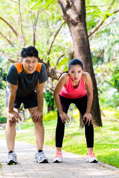 Pareja asiática toma descanso sin aliento de correr