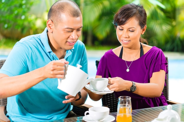 Pareja asiática tomando un café en el porche de casa