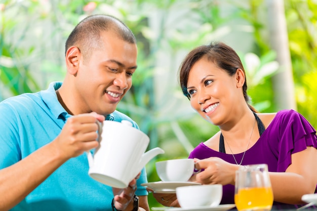 Pareja asiática tomando un café en el porche de casa