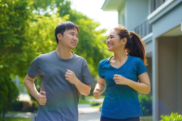 Una pareja asiática trota en el vecindario para la salud y el bienestar diarios, tanto físicos como mentales y un antídoto simple para el estrés diario y para socializar de manera segura.