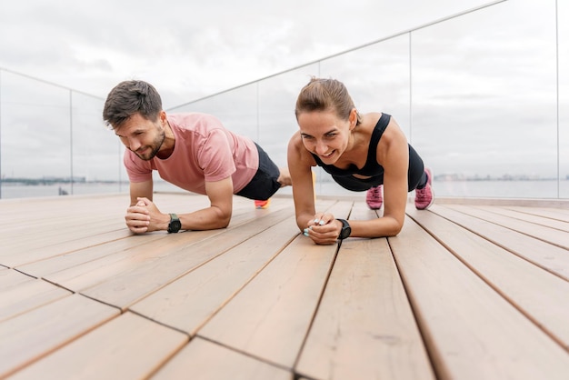 Pareja de atletas entrenando tablón en ropa deportiva Motivación amigos haciendo ejercicio físico juntos