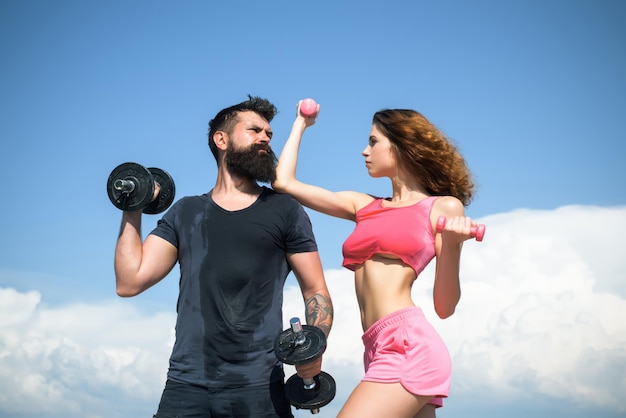 Foto pareja atlética de hombre y mujer en forma con pesas al aire libre pareja haciendo fitness fuera de forma joven