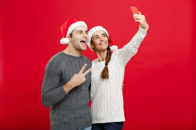 Pareja atractiva joven tomando un selfie por teléfono móvil celebrando en el día de Navidad.