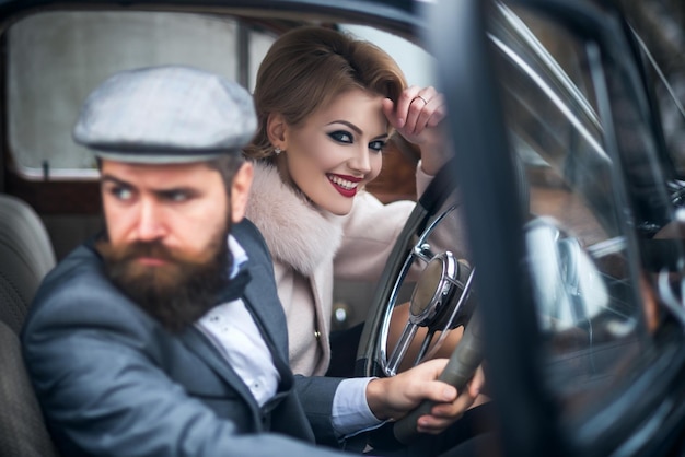 La pareja en auto retro jóvenes juntos mientras están sentados dentro de un auto antiguo