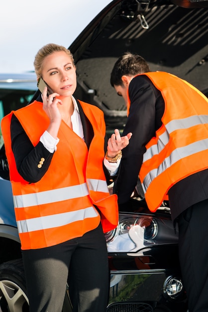 Pareja con avería del coche llamando a la empresa de remolque