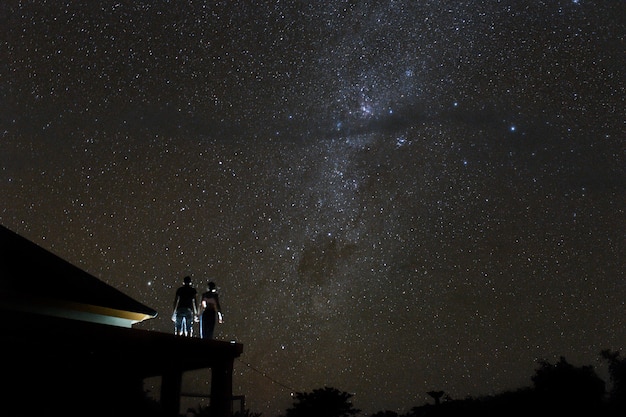 Pareja en la azotea mirando mliky way y estrellas en el cielo nocturno en la isla de Bali.