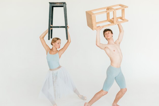 Pareja de bailarines de ballet moderno posando con sillas