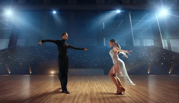 Pareja de bailarines realizan bailes latinos en un gran escenario profesional