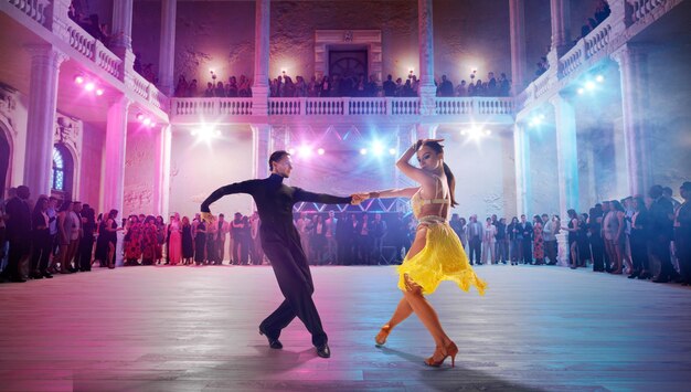 Pareja de bailarines realizan bailes latinos en un gran escenario profesional