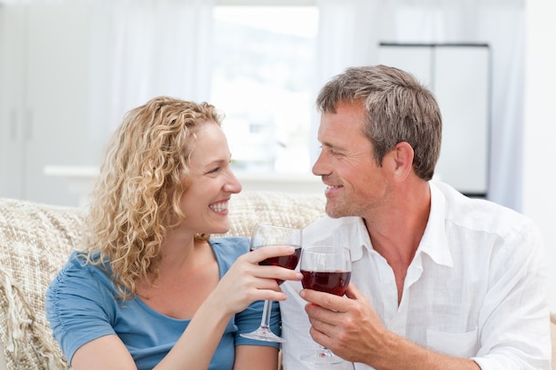 Pareja bebiendo vino tinto en la sala de estar