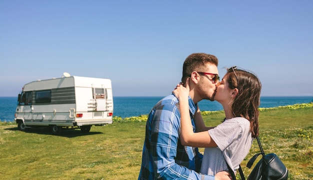 Pareja besándose cerca de la costa con una caravana