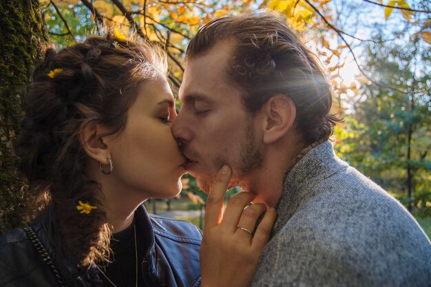 Foto pareja besándose contra el tronco del árbol