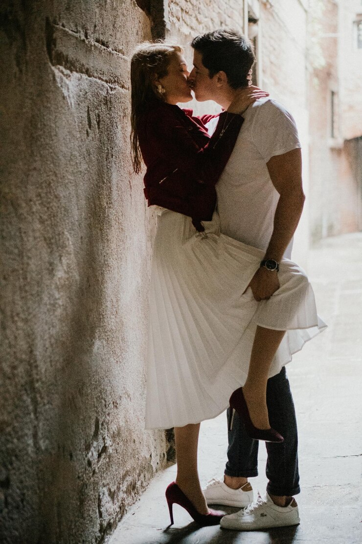 Foto una pareja besándose mientras están de pie contra la pared