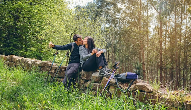 Pareja besándose mientras hace un descanso para hacer trekking