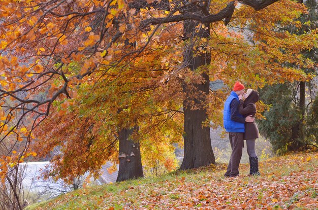 Pareja besándose en el parque otoño en un día soleado