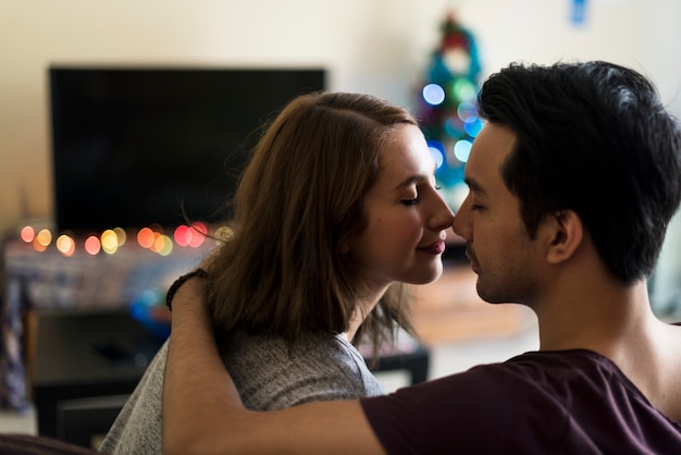 Pareja besándose en el sofá en casa