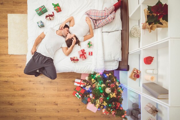 La pareja besándose yacía en la cama con regalos. vista desde arriba