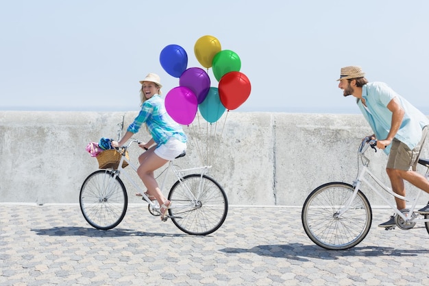 Pareja en bicicleta con globos bajo el sol