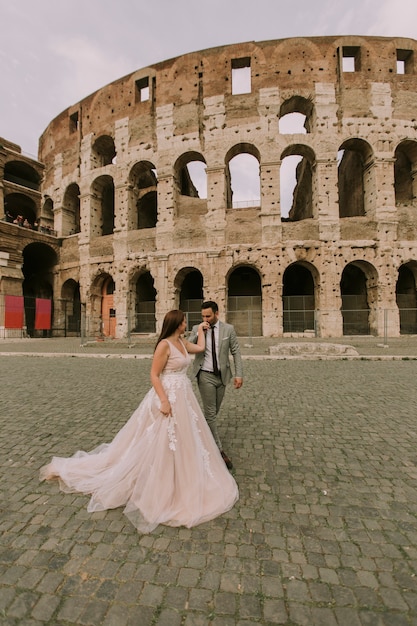 Foto pareja de boda cerca del coliseo en roma, italia