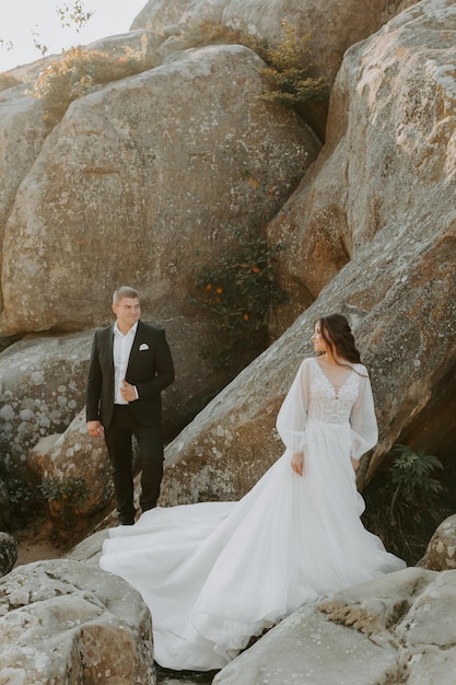 Pareja de boda. De pie cara a cara con las verdes colinas de fondo.