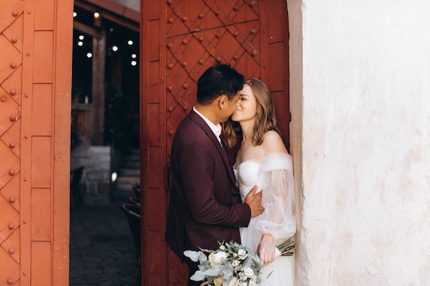 Una pareja de bodas internacionales, una novia europea y un novio asiático, caminan juntos por la ciudad