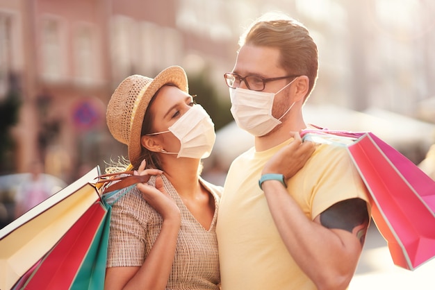Una pareja con bolsas de la compra y máscaras protectoras por coronavirus