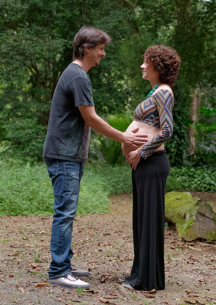 Pareja brasileña esperando bebé al aire libre tocando el vientre